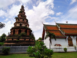 Fototapeta na wymiar Red brick stupa temple near beautiful building with red roof. Traditional architecture in Chiang Mai, Thailand.
