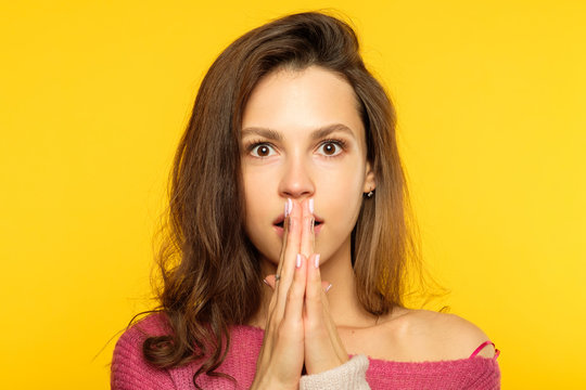 surprised shocked astonished amazed girl covering mouth with hand. unbelievable news. young beautiful woman on yellow background. emotional facial expression.