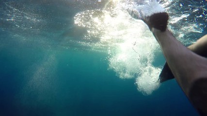 POV of man's legs swimming with flippers