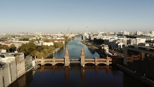 A wide shot of Berlin with many famous buildings. A typical yellow tram crosses the picturesque bridge called Oberbaum.