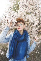 Young redhead woman surrounded by flowers