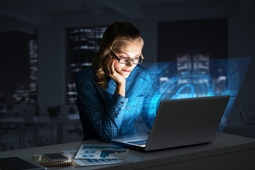 Beautiful blonde in dark office working on laptop and getting net access