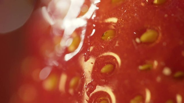 Macro shot of drop of water flowing from red strawberry