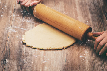 Frau beim ausrollen von Plätzchenteig oder Teig für Kekse mit Nudelholz