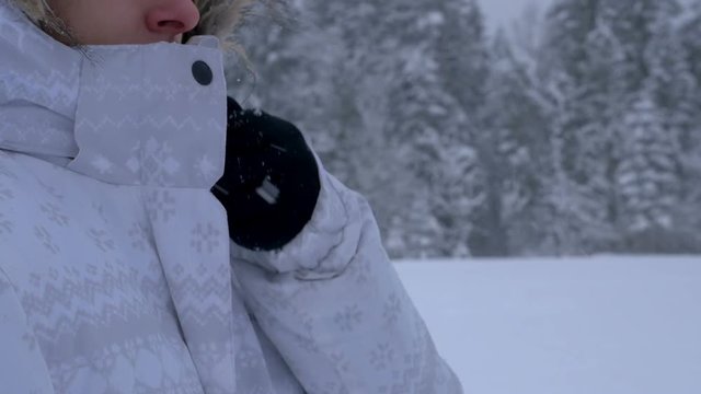 Young woman zipping up a jacket and walking away in winter at a light snowing