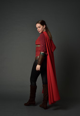 full length portrait of brunette girl wearing red medieval costume and cloak. standing pose  in...