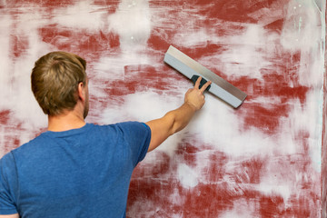 man plastering wall with taping knife