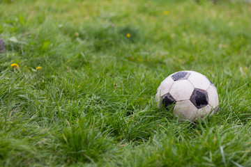 old dirty peeled soccer ball on the grass