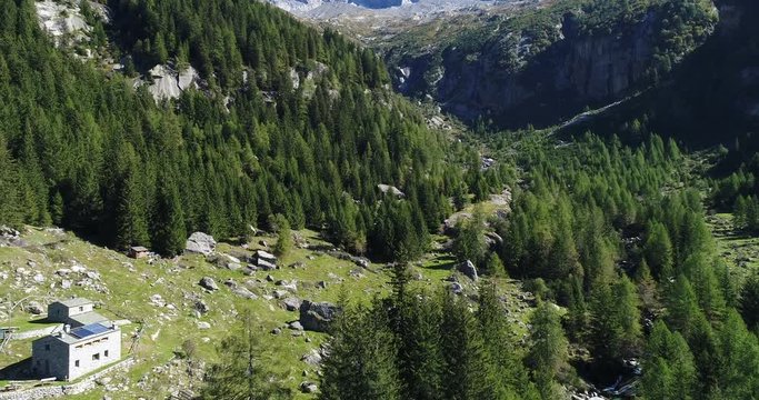 Flying forward in an alpine valley with coniferous forests and rock faces. Val di Mello, Valtellina, Italian Alps. This valley is famous for sport climbing. Aerial shot made with drone.