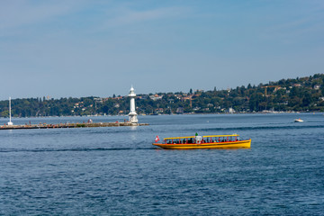 The Jet d'eau, landmark of the city of Geneva, with a yellow taxi boat in front. 500l water/s are...