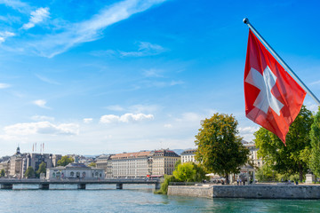 Swiss flag in front of the geneve skyline, cathedrale saint-pierre geneve, yellow boat and a...