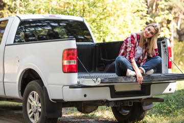 happy attractive woman sitting in trunk of pick up car outdoors © LIGHTFIELD STUDIOS