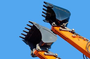 Black excavator buckets raised up on the background sky