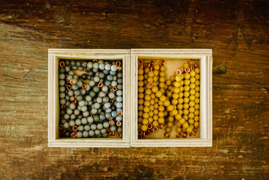 Boxes with beads to learn to count in a montessori classroom on aged wood.