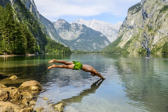 Young man jumps into Lake Obersee, swimming, mountain lake, mountain landscape, in the back Watzmann massif, Salet am Konigssee, Berchtesgaden National Park, Berchtesgadener Land, Upper Bavaria, Bavaria, Germany, Europe