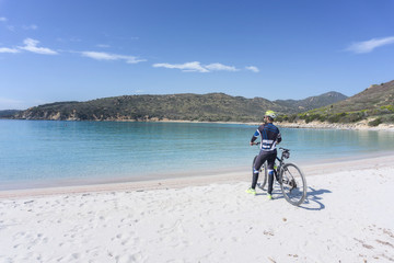 Cyclist on beach, Villasimius, Sardinia, Italy
