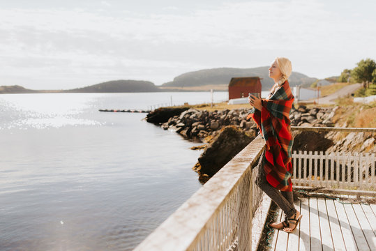 Woman enjoying morning drink on balcony by sea, Halifax, Canada