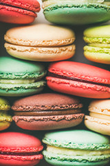 Flat-lay of sweet colorful French macaroon cookies stacked in rows, top view, vertical composition