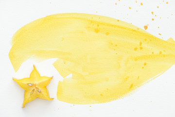 top view of sweet carambola on white surface with yellow watercolor