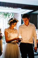 Happy bride hold and groom keep a family candle burning on the w