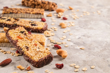 Mixed gluten free granola cereal energy bar with dried fruit & various nuts, gray concrete background. Healthy vegan super food, fitness dieting snack for sporty lifestyle. Top view, copy space.