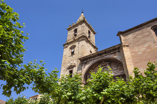 Spain, La Rioja, Navarrete: Steeple tower of pilgrim Church of Santa Mar&iacute;a de la Asuncion in the city center of the Spanish town with green trees and blue sky - concept Way of St. James pilgrimage