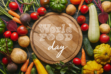 Variety of colorful vegetables by cutting board with "world food day" lettering