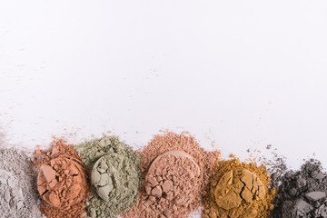 Set of different cosmetic clay mud powders on white background