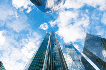 blue sky with clouds and tops of glass skyscrapers