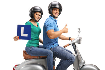 Young woman with an L-sign and a young man holding his thumb up riding a vintage scooter
