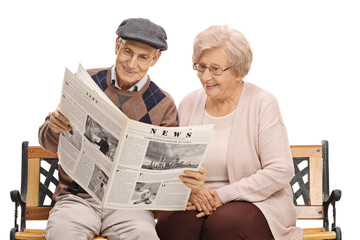 Elderly man and woman reading a newspaper together