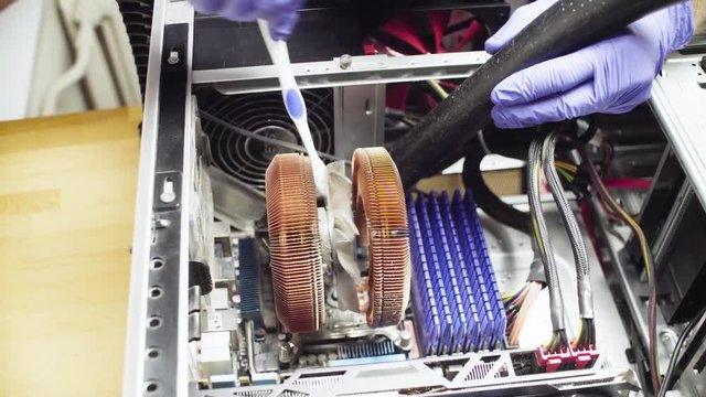 Crane shot. Repairing of computer. Male hands cleaning computer cooler from dust with a vacuum cleaner and toothbrush