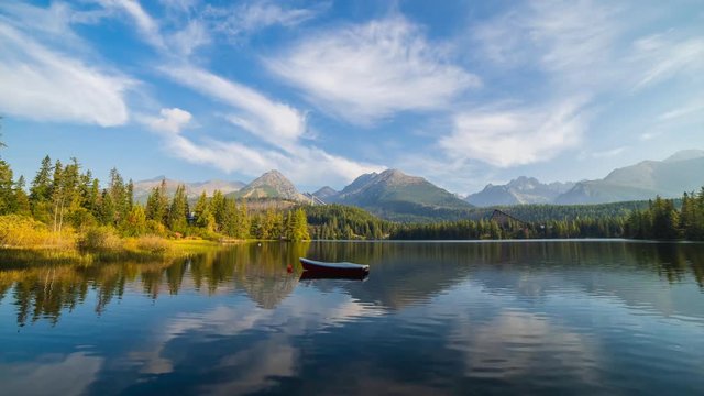 Time lapse of mountain scene with mountain hotel next to a lake with boat. Scenic view of Strbske Pleso, High Tatras National Park, Slovakia.
