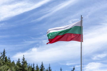Bulgarian national flag on a pole against silky clouds.