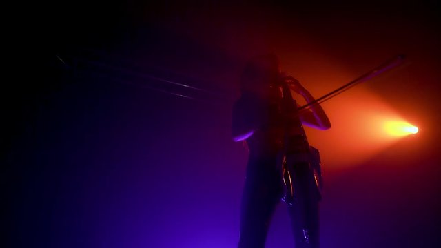 Cellist with electronic cello performs on stage.