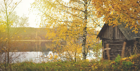 Fall days. Wooden hous near by river. Colorful autumn.