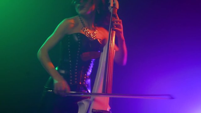 Cellist with electronic cello performs on stage.