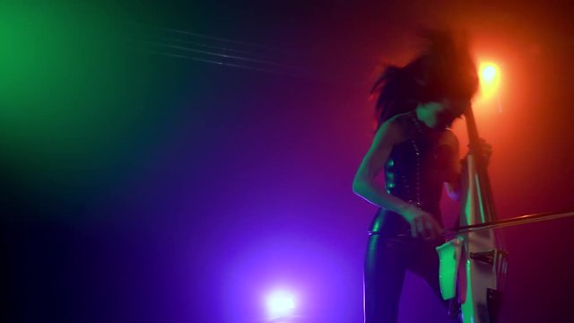 Cellist with electronic cello performs on stage.