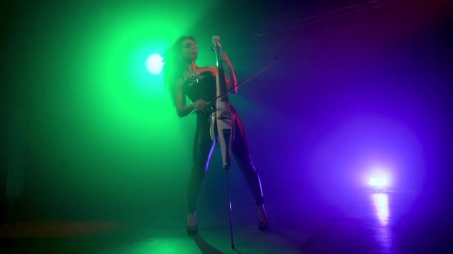 Cellist with electronic cello performs on stage.
