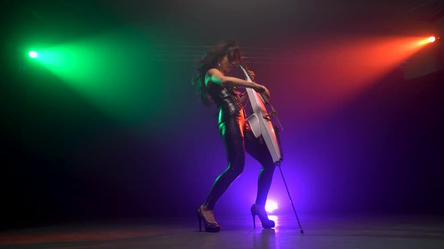 Cellist with electronic cello performs on stage.