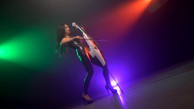 Cellist with electronic cello performs on stage.