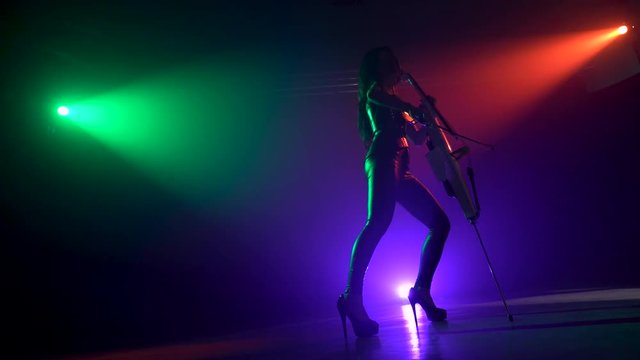 Cellist with electronic cello performs on stage.