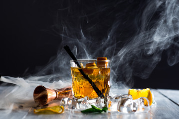 Whiskey cocktail with a smoke called smoking gun at the bar