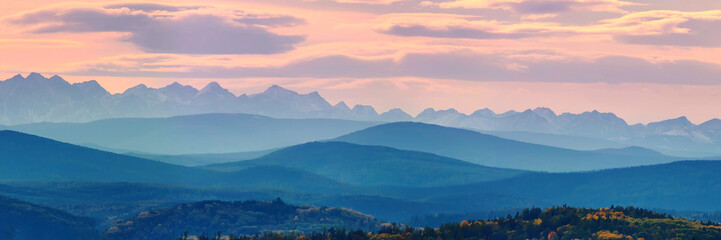 Wide angle panorama autumn forest,misty hills mountain tops in pink dawn