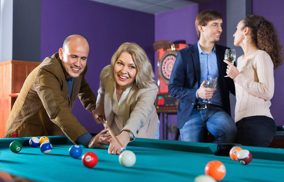 Relaxed cheerful positive smiling people playing billiard and darts