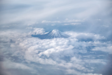 Top view of Fuji mountain and many clouds. View from window seat of airplane flying pass Fuji from Tokyo.