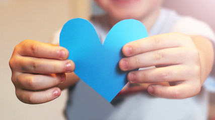 The child holds the paper blue heart