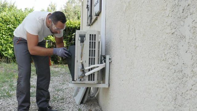 handsome young man electrician installing air conditioning in a client house

