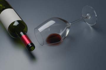 close up of a red wine glass and an empty bottle of red wine on the table