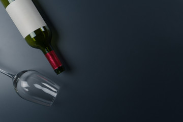 top view of an empty wine glass and a bottle of red wine on the dark table